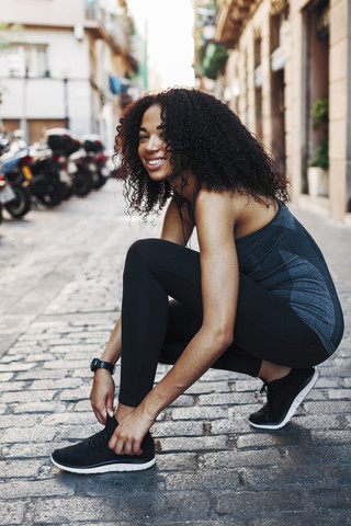 Spain, Barcelona, sportive young woman tying her shoe stock photo