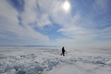 Russia, Lake Baikal, man walking on frozen lake - GNF001352