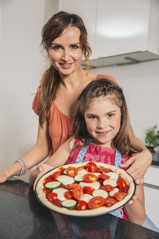 Mutter und Tochter präsentieren selbstgemachte Pizza, lizenzfreies Stockfoto