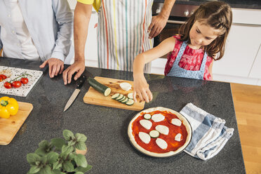 Little girl garnishing homemade pizza in the kitchen - MFF001754
