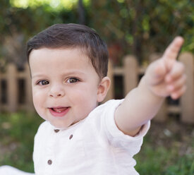 Porträt eines lächelnden kleinen Jungen, der mit dem Finger zeigt - RAEF000229