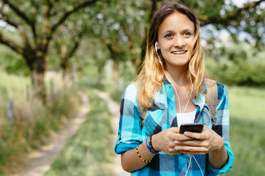 Portrait of smiling teenage girl with smartphone and earphones - GIOF000069