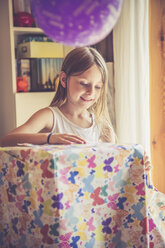 Lächelndes kleines Mädchen beim Auspacken eines Geschenks - SARF002026