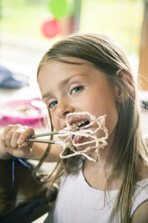 Portrait of little girl licking whipped cream from stirrer - SARF002027