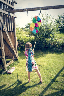 Mädchen mit Pinata in Form einer Acht im Garten - SARF002031