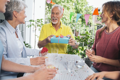 Älterer Mann hält Geschenk bei Familienfeier, lizenzfreies Stockfoto