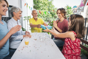 Grandfather and granddaughter exchanging a gift at family party - MFF001713