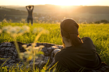 Germany, couple on a meadow watching for sunrise - MIDF000494