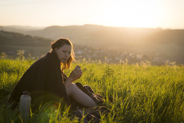 Deutschland, Frau beim Frühstück auf einer Wiese bei Sonnenaufgang - MIDF000496