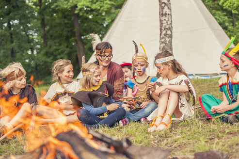 Deutschland, Sachsen, Indianer und Cowboyparty, Kinder sitzen am Lagerfeuer - MJF001655