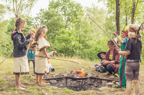 Deutschland, Sachsen, Indianer und Cowboy-Party, Kinder, die Marshmallows auf Stöcken rösten - MJF001677