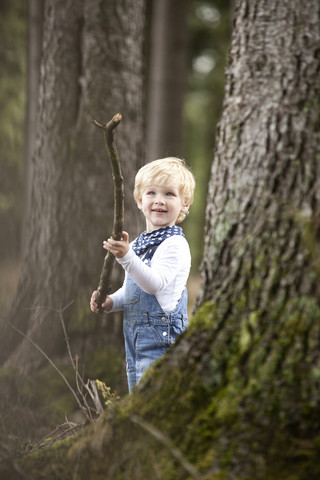 Kleiner Junge mit Ast im Wald, lizenzfreies Stockfoto