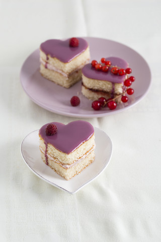 Kleine Biskuitkuchen in Herzform mit Himbeersahne und Johannisbeergelee, lizenzfreies Stockfoto