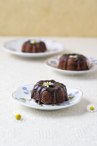 Mini-Schokoladenkuchen mit essbaren Blumen auf Tellern, lizenzfreies Stockfoto