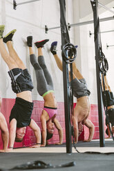CrossFit-Athleten machen Handstand-Liegestütze an einer Wand - MADF000399
