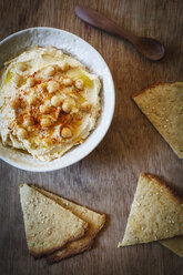 Schale mit Hummus und Fladenbrot auf Holz - EVGF002178