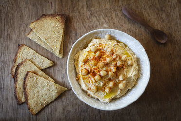 Schale mit Hummus und Fladenbrot auf Holz - EVGF002179