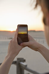 Teenage boy taking picture of sunrise with his smartphone - MEMF000835