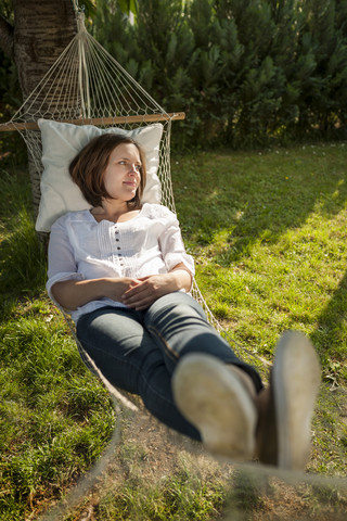 Frau entspannt sich in einer Hängematte im Garten, lizenzfreies Stockfoto