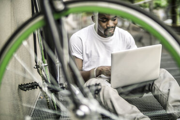 Portrait of young man with bicycleand laptop - RIBF000118