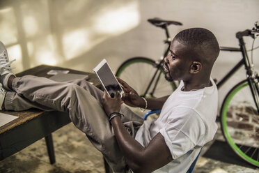 Porträt eines jungen Mannes mit digitalem Tablet in seinem Atelier - RIBF000122