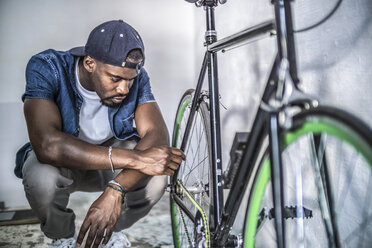 Young man checking his bicycle - RIBF000125