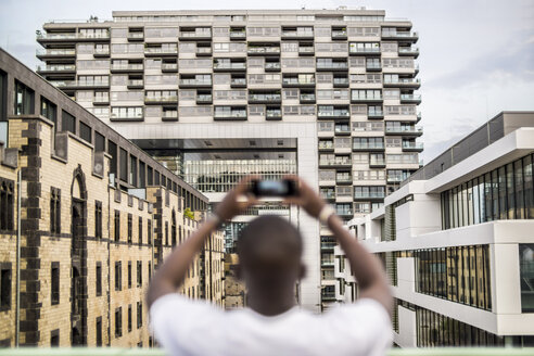 Deutschland, Köln, junger Mann beim Fotografieren mit Smartphone - RIBF000135