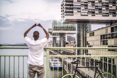 Germany, Cologne, young man taking a picture with smartphone - RIBF000137