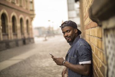 Portrait of young man with baseball cap smartphone - RIBF000140