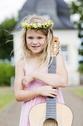 Deutschland, Holzwickede, Porträt eines lächelnden kleinen Mädchens mit Gitarre und Blumenkranz - GDF000778
