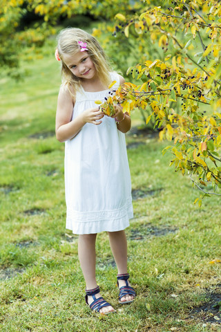Porträt eines lächelnden Mädchens mit weißem Sommerkleid und Blumen, lizenzfreies Stockfoto