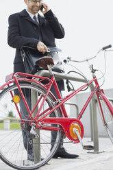 Geschäftsmann im Freien mit Aktentasche und Fahrrad beim Telefonieren - WESTF021285