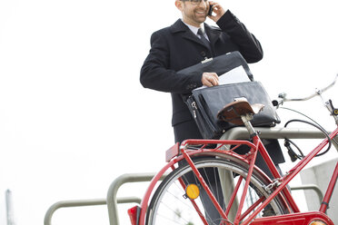 Geschäftsmann im Freien mit Aktentasche und Fahrrad beim Telefonieren - WESTF021286
