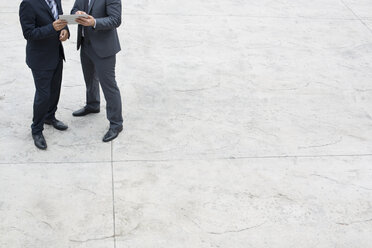 Two businessmen with digital tablet standing on square - WESTF021334