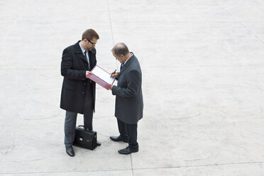 Zwei Geschäftsleute auf dem Platz unterzeichnen eine Urkunde - WESTF021339