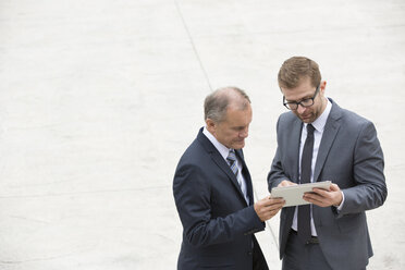 Zwei Geschäftsleute mit digitalem Tablet auf einem Platz stehend - WESTF021367