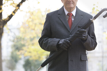 Businessman outdoors holding umbrella - WESTF021371