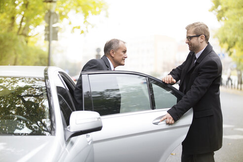 Chauffeur öffnet Autotür für aussteigenden Geschäftsmann - WESTF021377