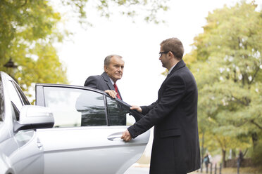 Chauffeur öffnet Autotür für aussteigenden Geschäftsmann - WESTF021351