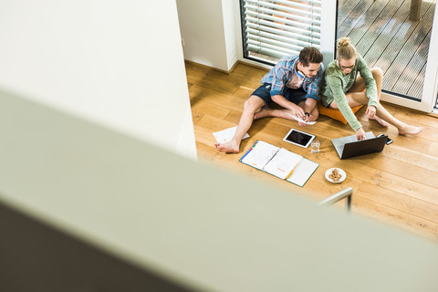 Zwei Studenten sitzen auf einem Holzboden und lernen, lizenzfreies Stockfoto