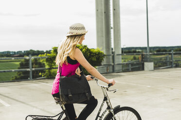 Teenage girl riding bicycle on parking level - UUF004859