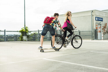 Glückliches junges Paar mit Fahrrad und Skateboard - UUF004861