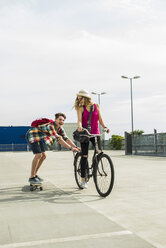 Glückliches junges Paar mit Fahrrad und Skateboard - UUF004862