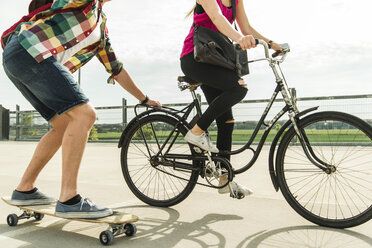 Junges Paar fährt Fahrrad und Skateboard - UUF004863