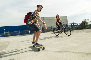 Glückliches junges Paar mit Fahrrad und Skateboard - UUF004864