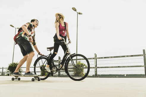 Glückliches junges Paar mit Fahrrad und Skateboard - UUF004867