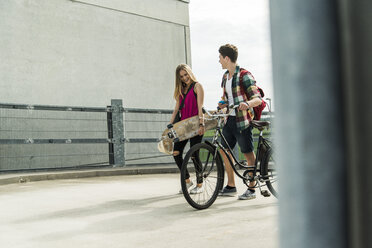 Glückliches junges Paar mit Fahrrad und Skateboard - UUF004875