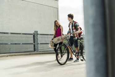 Happy young couple with bicycle and skateboard - UUF004875