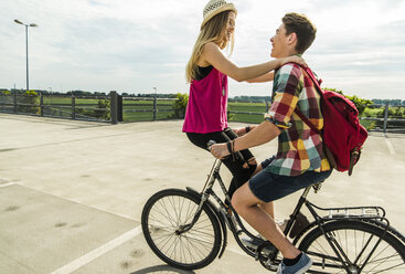 Glückliches junges Paar zusammen auf einem Fahrrad - UUF004877