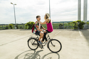 Glückliches junges Paar zusammen auf einem Fahrrad - UUF004879